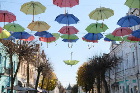 colorful umbrellas street decoration with one inverted fallen umbrellaの写真素材