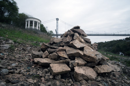 Pyramid of gray stones on the bank of a mountain river. Zen and harmony concept. Stone tower in the park with alcove and bridge background.の写真素材