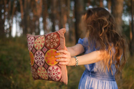 Girl with hair covering the face in the forest. Woman hold her pillow in hands.の写真素材