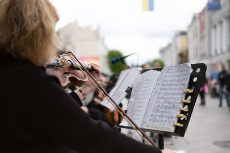 Girl with violin with other musicians in the street playing music at festival.の写真素材