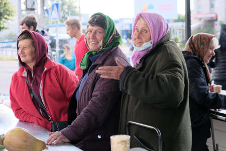 Zhytomyr, Ukraine - October 10, 2020: three old grandmothers at a traditional market communicate with buyers and sell products.のeditorial素材