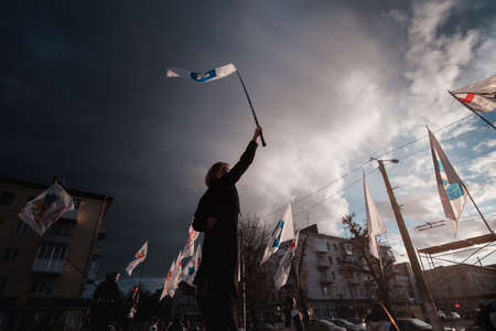 Zhytomyr, Ukraine - October 19, 2020: silhouette of street protestors with flags and banners at dramatic sky backgroundのeditorial素材