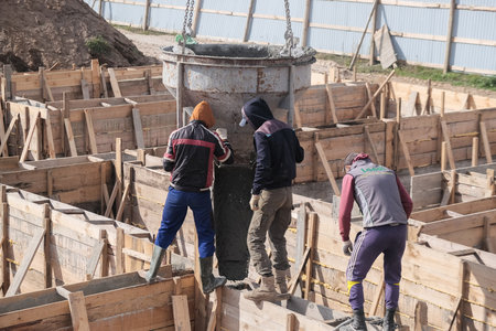 Zhytomyr, Ukraine - October 5, 2020: building workers at construction site doing concrete works with barrel.のeditorial素材