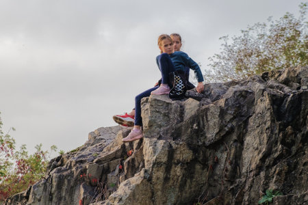 Zhytomyr, Ukraine - October 11, 2020: Two young girls sitting on rocks in nature. Dangerous situation about safety.のeditorial素材