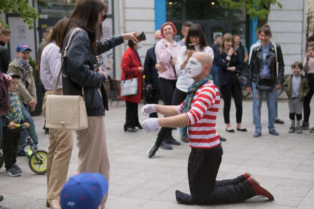 Zhytomyr, Ukraine - May 15, 2021: Professional mime artist performing different emotions and interacts with people. Man with a hat begging for moneyのeditorial素材