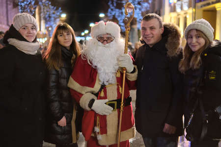 Zhytomyr, Ukraine - December 19, 2021: Santa Claus at Christmas market hugs people at night.のeditorial素材
