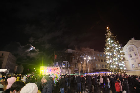 Zhytomyr, Ukraine - December 19, 2021: People gathered at night to celebrate the new year. Scene and christmas tree on background.のeditorial素材