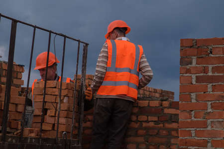 Zhytomyr, Ukraine - October 1, 2020: Workers laying bricks on construction site at dramatic sky background.のeditorial素材