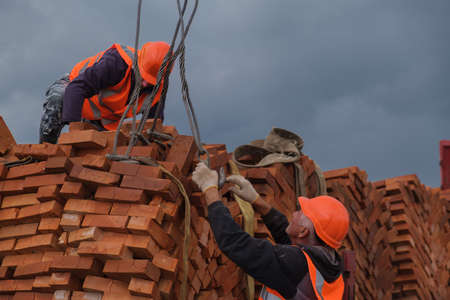 Zhytomyr, Ukraine - October 1, 2020: Crane driver deliver a pallet bricks on construction or building site.のeditorial素材