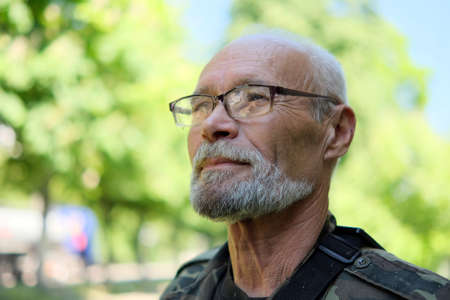 Zhytomyr, Ukraine - October 10, 2021: Portrait of elderly man with glasses standing in house yard. Concept of old age, optimistic view of the future generationsのeditorial素材