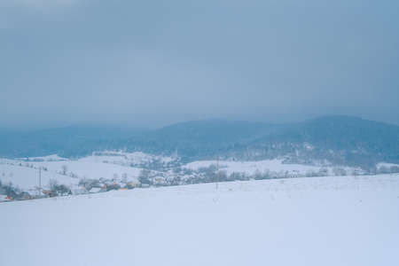 Snowing landscape in Europe. Lonely small village before the storm at mountains.の写真素材