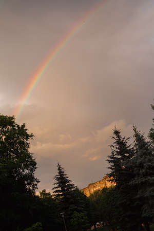 rainbow light sunset at cloudy sky, dark trees in the city.の写真素材