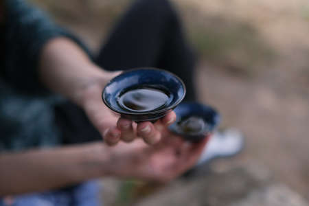 Girl hand holding blue cup with tea. A tea ceremony at rocks. The way of spending time with friends...