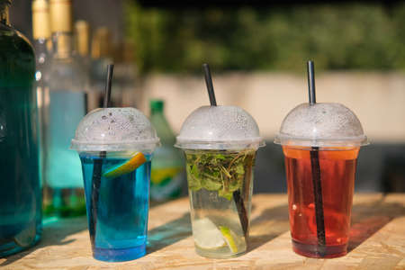 Lemonade in plastic glasses. green, red and yellow drinks on food market.の写真素材