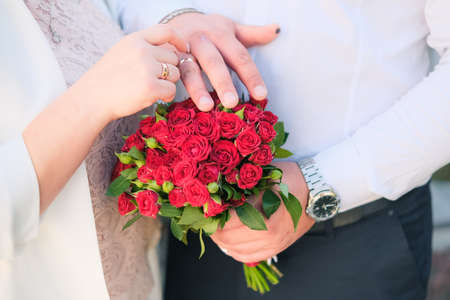 Hands and rings on wedding red bouquet.の写真素材