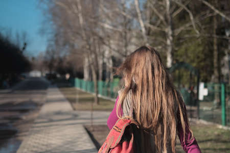 Young woman standing on street. Young casual girl back view.