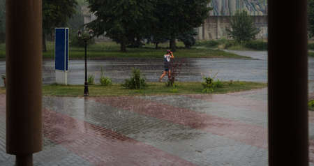 heavy rain drops falling on city street during downpourの写真素材