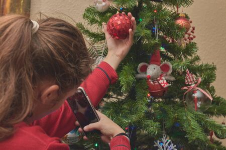 girl decorating christmas tree with mobileの写真素材