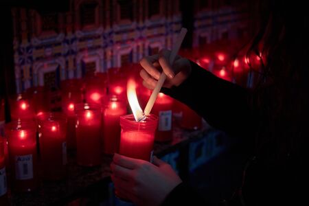 girl lighting red candle in Olvera hermitage with Sevillian tiles in background
