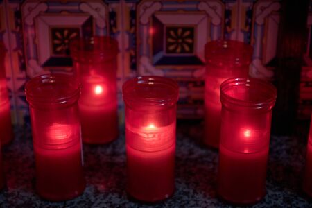 girl lighting red candle in Olvera hermitage with Sevillian tiles in backgroundの写真素材