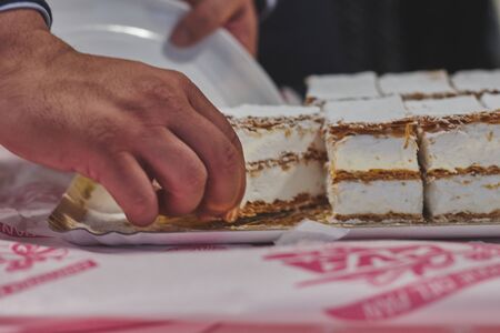 man taken milhojas of Meringue over table with his handの写真素材
