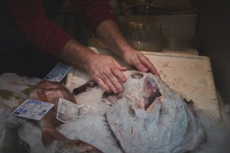 fishmonger preparing flounder in market