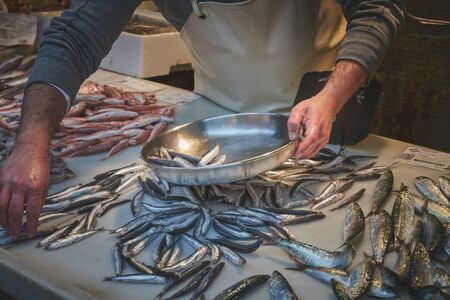 fishmonger preparing flounder in market