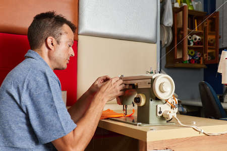 Qualified workman upholstering furniture in repair furniture workshopの写真素材