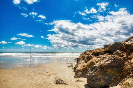 A low angle shot of a beach with waves breaking and a beautiful cloudy day.
