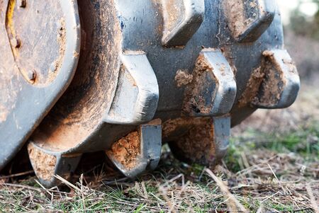 A closeup of a soil compactor on the bucket of a track hoe.