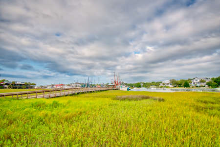 Shrimp boats in the distance across a salt-marsh with a boardwalk to get to them on Shem creek in Mount Pleasant, South Carolina near Charleston.の写真素材