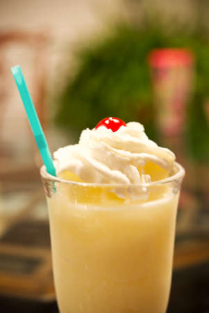 A delicious Pina Colada drink with a cherry and a straw in a tall glass.の写真素材