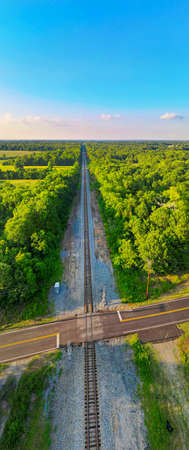 An aerial view of a railroad cutting through a forest.
