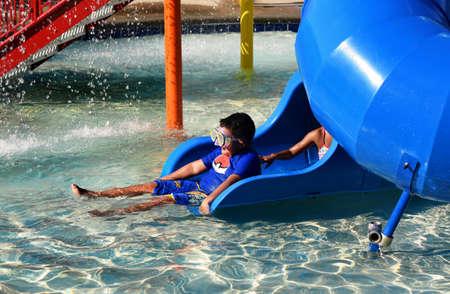 Kids playing in the water at a small water park at a community pool.