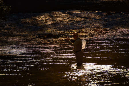 A silhouette of a fly fisherman in a North Carolina mountain trout stream.