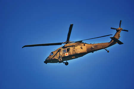 A medical helicopter flying low against a clear blue sky.