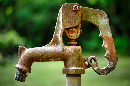 A close up of an old exterior faucet with a blurred background.