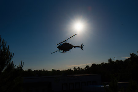 Silhouette of a helicopter flying in the blue sky.の写真素材