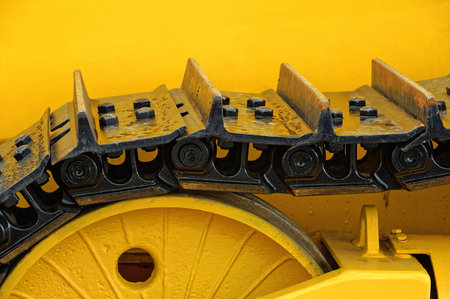Fragment of the crawler mechanism of the yellow excavator.