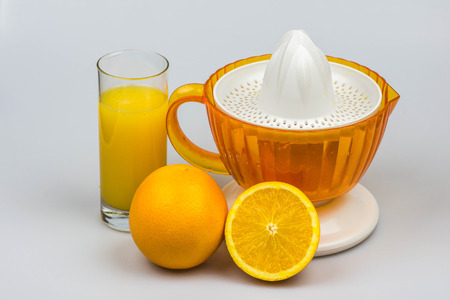 Citrus juicer with fresh squeezed juice, oranges and lemon isolated on a white background