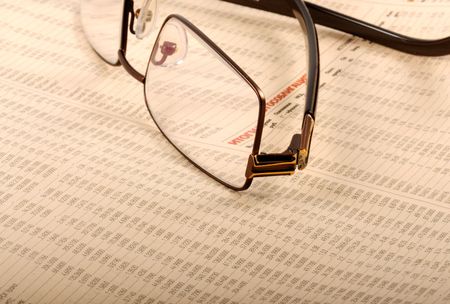 Glasses lying on a folded newspaper with business report   の写真素材