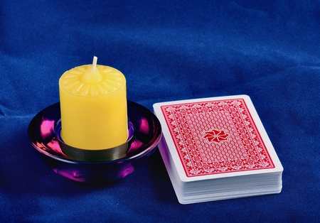 The back of a playing cards lays on a dark blue fabric, near locates a candleのeditorial素材