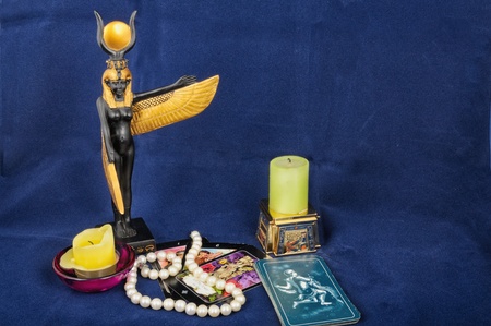 The pack tarot lays on a dark blue fabric, near locates a candle and statuette of the Egyptian goddess Isisの写真素材