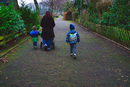Mother with stroller and small children taking a walkの写真素材