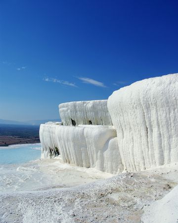 Winter-like landskape with white travertine instead of snow, limestone pool instead of ice and improbably blue sky in the background の写真素材