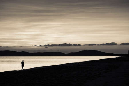 A man walking on the beach after sunsetの写真素材