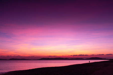 unset at the beach and silhouette of a man walkingの写真素材
