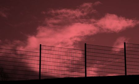 Black Fence against threadening red skyの写真素材