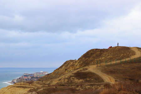 winding mountain road on top of a mountain silhouette of a man against a cloudy skyの写真素材