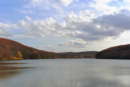 landscape lake in the mountains against a background of white clouds in a blue skyの写真素材